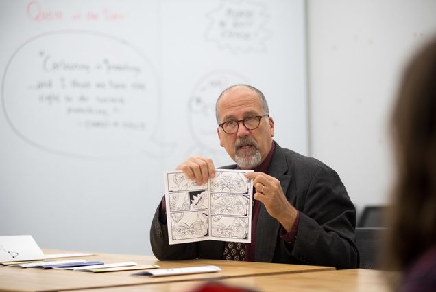 Paul Karasik who teaches “drawing into animation” at the College of Fine Arts holds up a book of comics to show his class