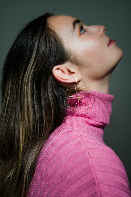 Maya Malekian (COM’20) shows off gold wire earrings in the shape of a flower made by her mom
