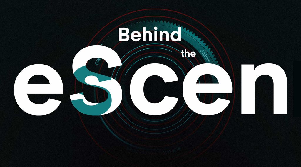 Detail photo of a camera lens in the dark. Text embedded in the photo says 'Behind the Scenes'
