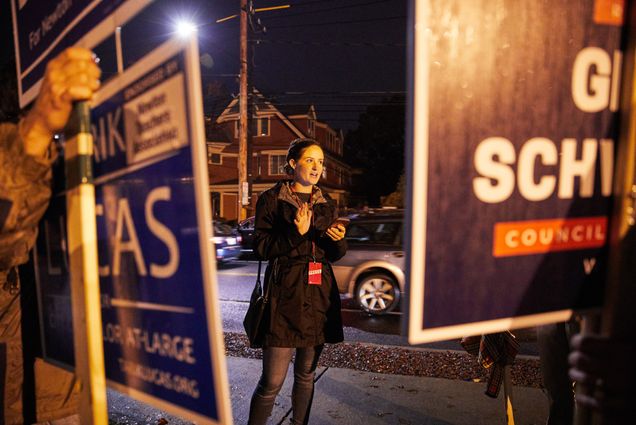 COM student Abby Parsons stands between two people holding up signs for political candidates.
