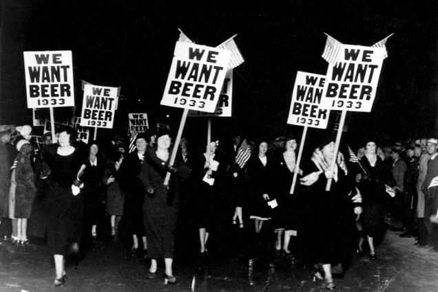 A group of women march holding signs that read "We want beer 1933" and American flags.