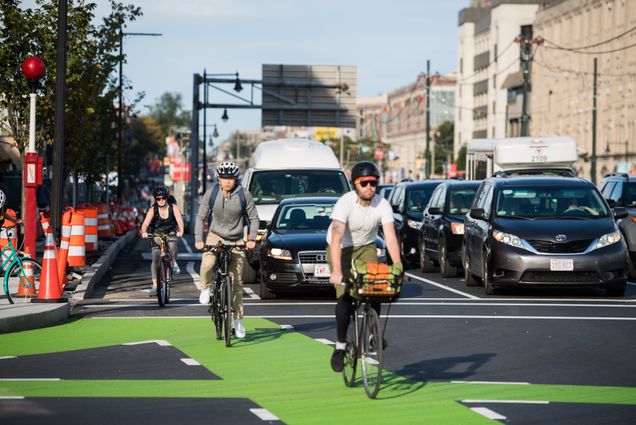 Bicyclists and cars travel along comm ave