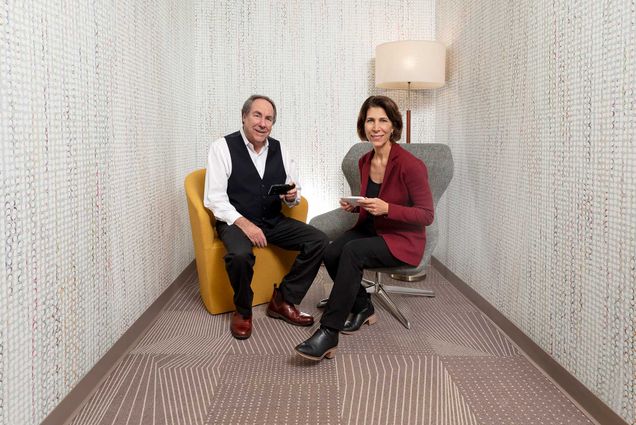 Paul Schneider and Debbie Danielpour seated in an office-like setting.