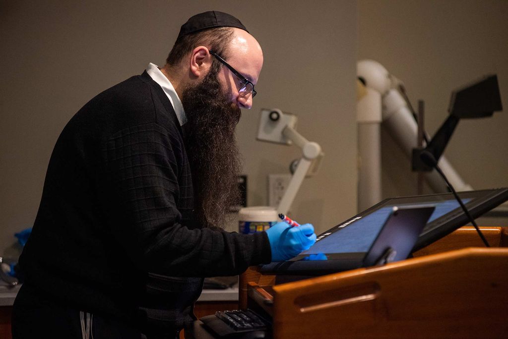 Remote teaching after Boston University sends students home during the coronavirus public health emergency, Binyomin Abrams writes on a smart tablet during his remote chemistry class.