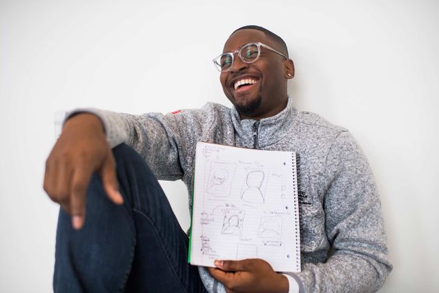 Boston University student Emmanuel Reid poses for a photo with some of his doodle drawings.