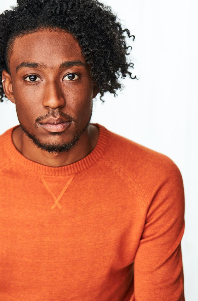 Portrait of Nicholas Walker in a bright orange shirt.