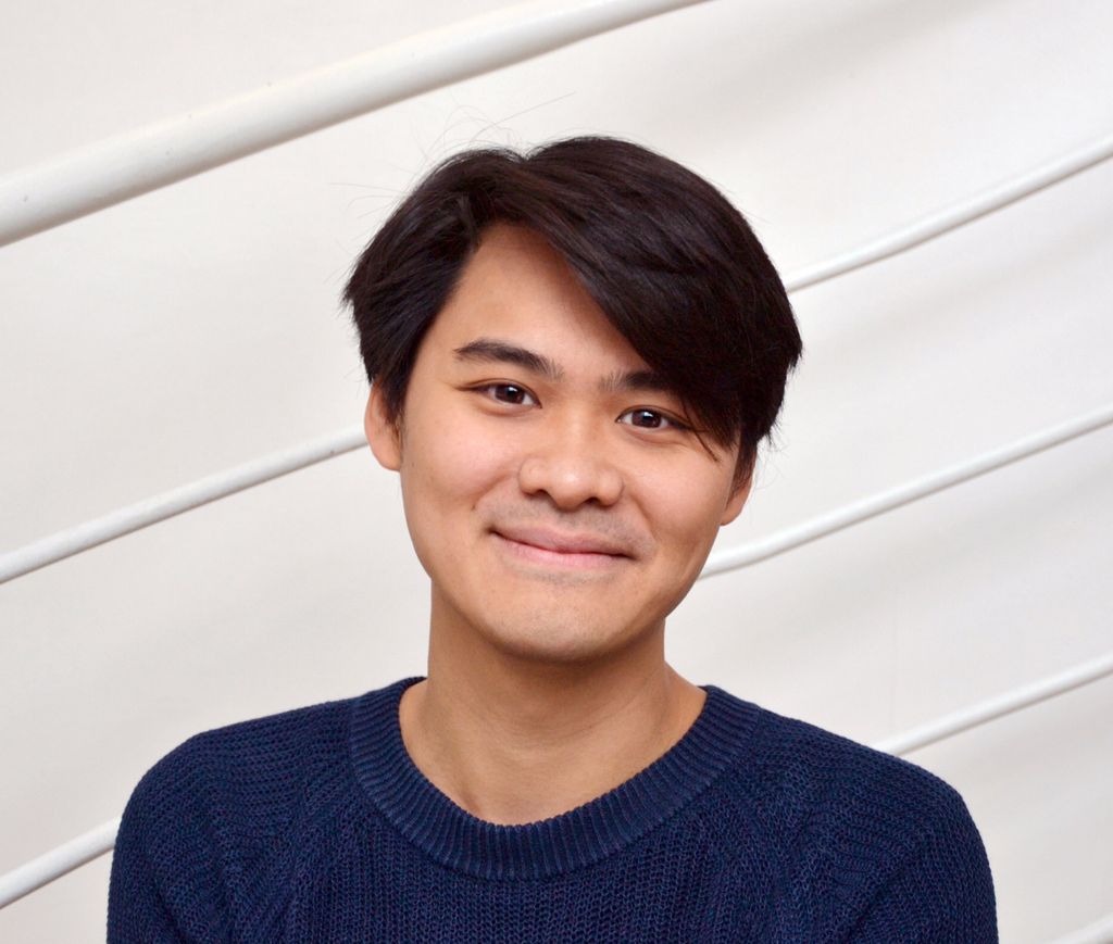 Portrait of Tak-Cheung Hui in a blue shirt on a gray stripped background.