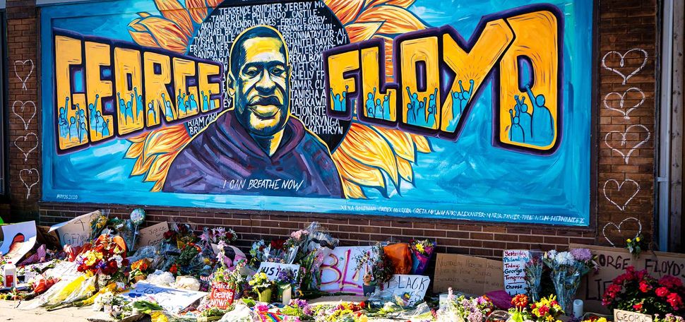 Brightly colored mural honoring George Floyd created during the Black Lives Matter protest in Minneapolis, Minnesota. The mural is a painting of Floyd with a sunflower behind him like a halo. "George Floyd" painted on either side of his portrait.