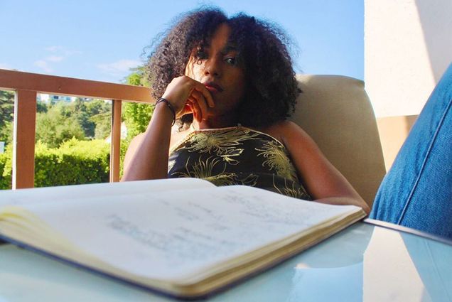 A photo of Natalie Guerrero sitting at a table with an open book in front of her
