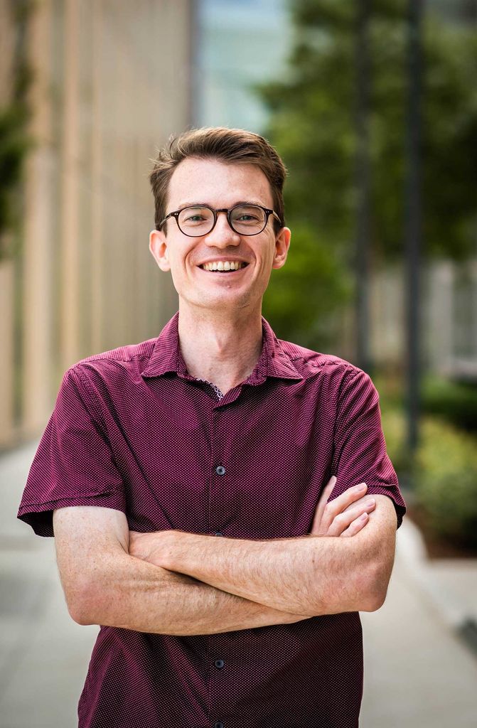 Portrait of Joseph Larkin, College of Arts & Sciences assistant professor of biology and physics, in a maroon polo shirt with his arms crossed.