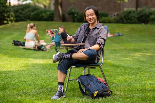 A photo of Aaron Hwang sitting at a desk outside smiling