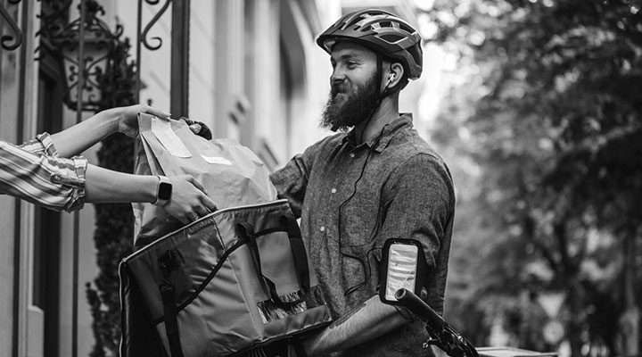 A photo of a delivery driver on a bike handing over someone's delivery
