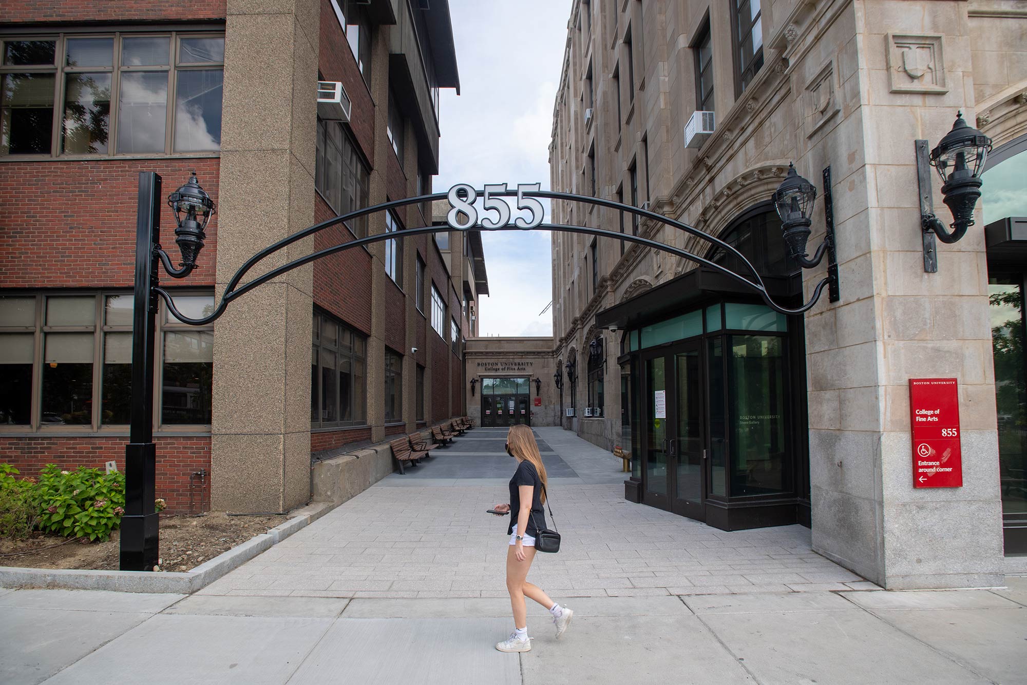 Photo of a student walking by the new additions to CFA, including an arch with the number 855.