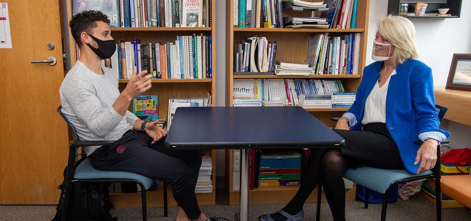 Diane Constantino (Sargent’81), director of BU’s Center for Stuttering Therapy, in her office with client Mason Blake (Wheelock’23). The two stage a therapy session. They both wear masks, Constantino wears a clear mask.