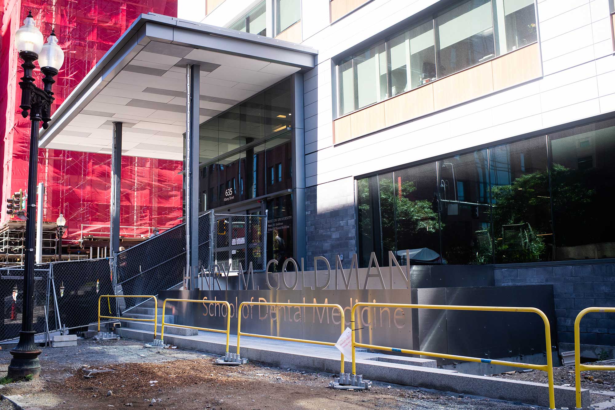 Photo of Construction at the Henry Goldman School of Dentistry  on August 30, 2020. Yellow barriers sit in front of the school's sign.