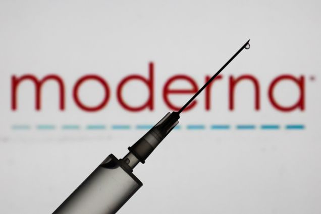 A syringe in front of text that reads "Moderna"