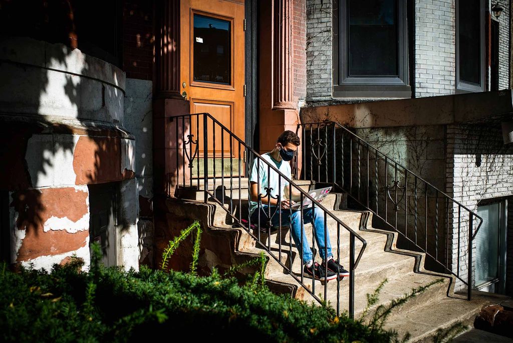 Faisal Halabeya participates in remote class via laptop from the steps of his apartment building