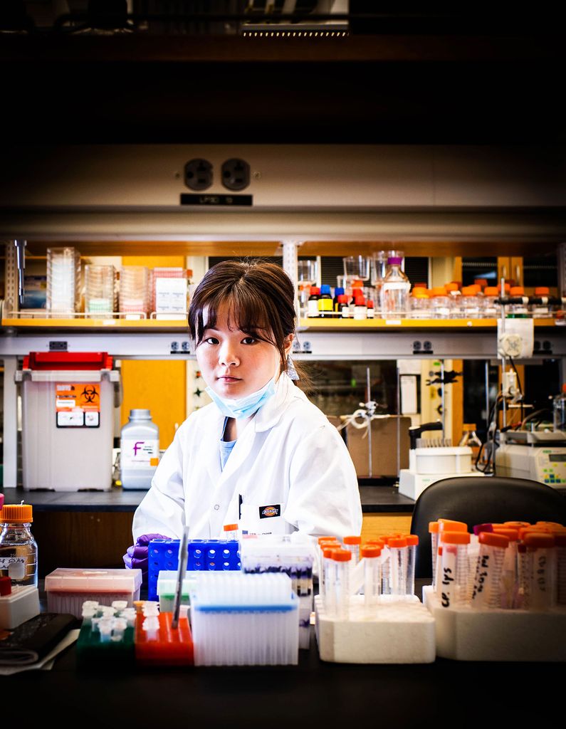 Portrait of Sunnie Kong (CAS'21, GRS'21) in a lab in a white lab coat with her mask pulled down.