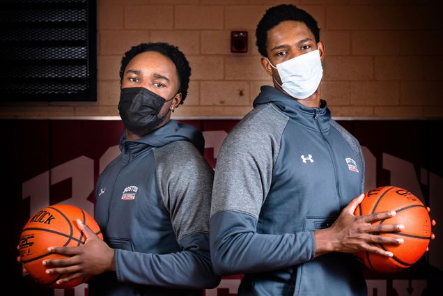 A photo of Walter Whyte and Jonas Harper standing next to one another, wearing masks, and each holding a basketball