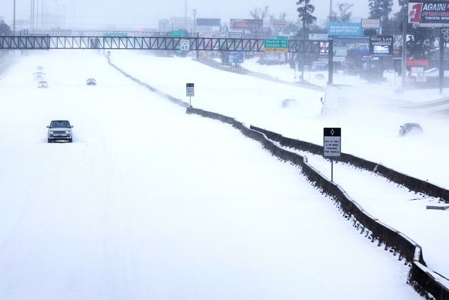 A photo of a snow covered highway in The Woodlands, Texas. Only one or two cars are visible on the road.