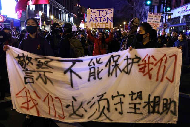 Activists carrying signs and banners participate in a vigil in response to the Atlanta spa shootings March 17, 2021 in the Chinatown area of Washington, DC.