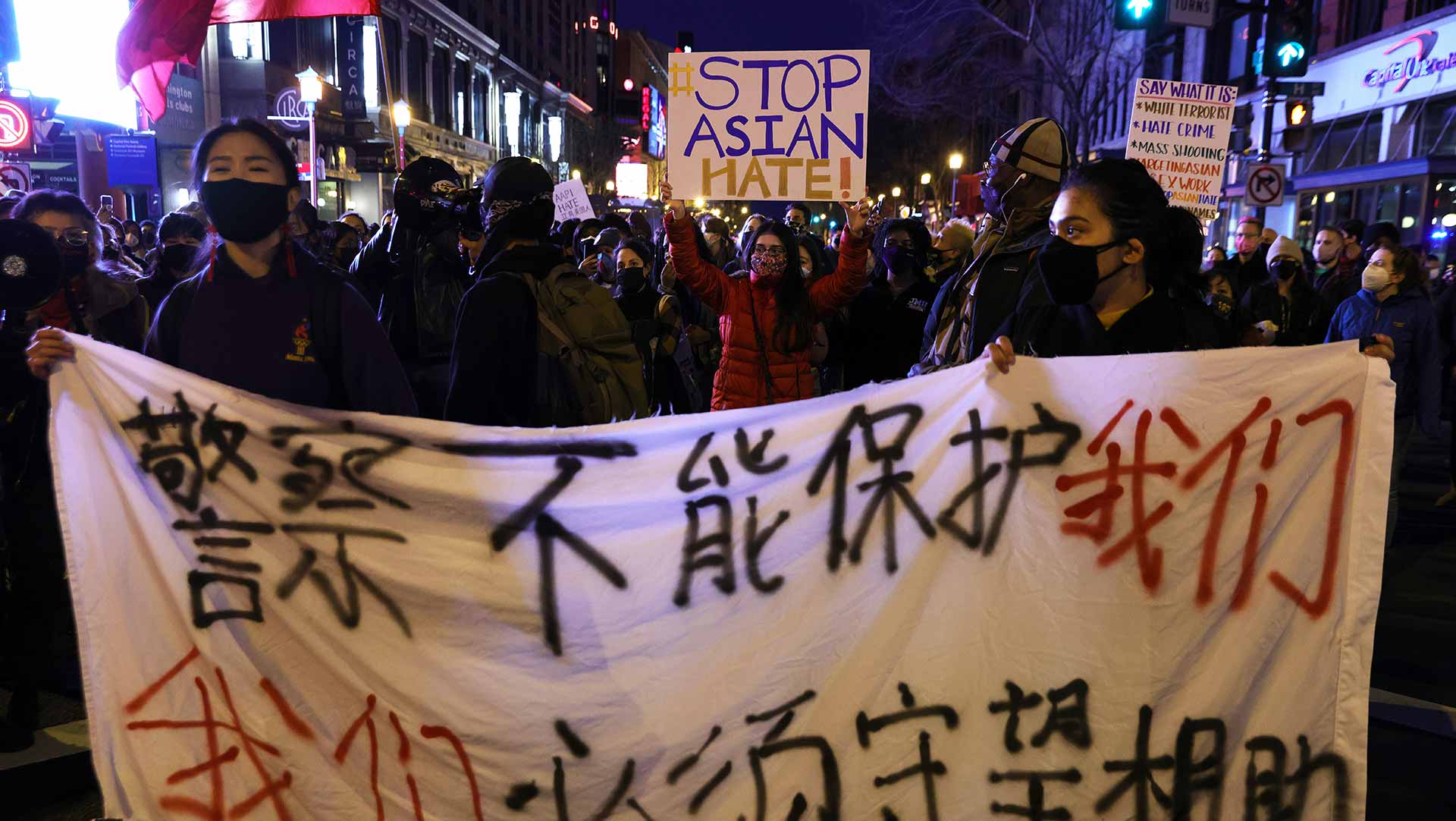 Activists carrying signs and banners participate in a vigil in response to the Atlanta spa shootings March 17, 2021 in the Chinatown area of Washington, DC.