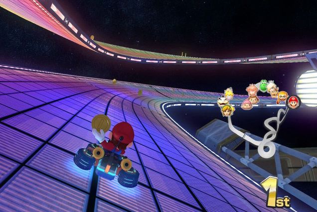 A photo of Mario Kart. Mario is visible in his kart holding a coin on the Rainbow Road level.