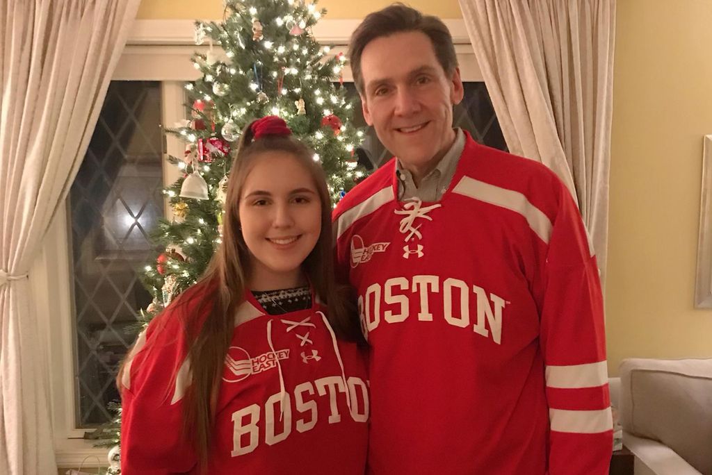 A photo of Rory Kallfelz (MET’21) and Alexandra Kallfelz (COM’21) wearing BU hockey jerseys in front of a christmas tree