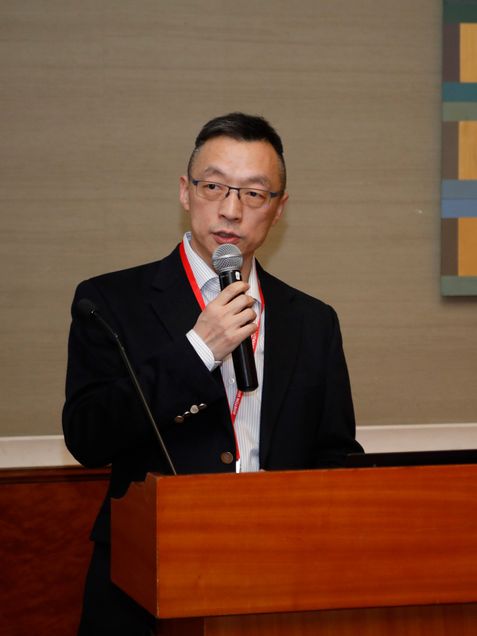 Photo of Haidong Pan (ENG’04) in a suit standing in front of a wooden podium with a microphone in his hand as he speaks.