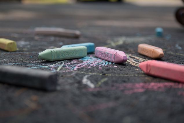 Photo of crayola sidewalk chalk pieces of various pastel colors laying on pavement.