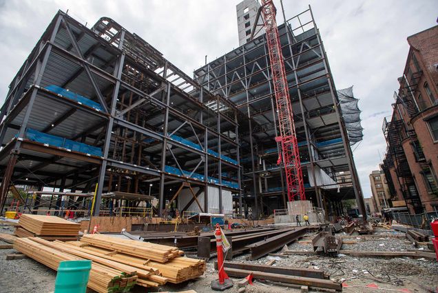 Photo of construction at the Data Science Center at 645-665 Commonwealth Avenue. You can see the skeleton of the building in steel beams, the concrete elevator shaft in the background, and a few construction workers on the ground.