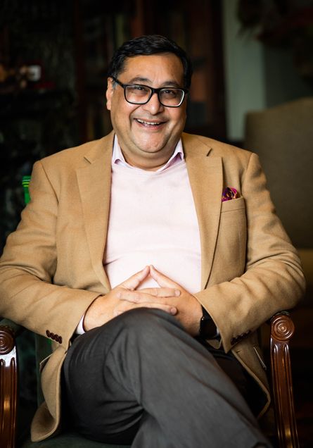 BU Dean of Pardee School of Global Studies, Adil Najam, sits in chair and smiles at camera in his office