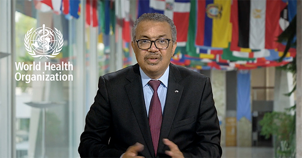 Photo of Tedros Adhanom Ghebreyesus, director-general of the World Health Organization (WHO). He is a middle aged brown-skinned man with salt-and-pepper hair and glasses. He is mid-speaking, as he delivers opening remarks during the launch of the report by the Rockefeller Foundation-BU Commission on Health Determinants, Data, and Decision-making (3-D Commission) Tuesday, September 21. The World Health Organization logo with a snake wrapped around a staff is overlaid on the image to his right, and flags hang from the ceiling behind him.