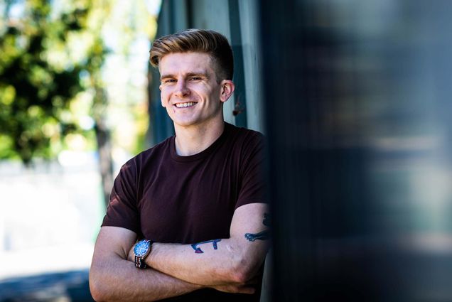 Portrait of Macken Murphy leaning against a wall with arms crossed.