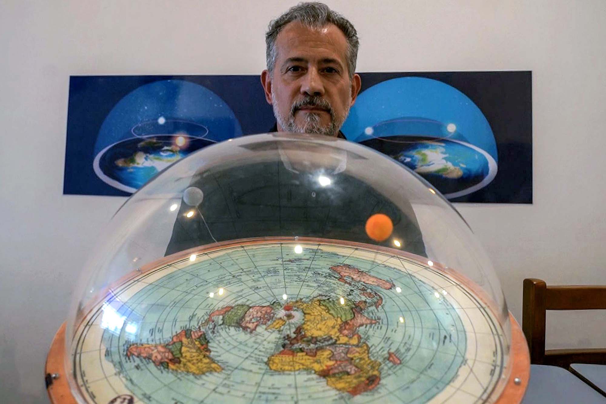 Flat-earth conspiracy theorist Anderson Neves displays a model of what he believes the planet really looks like - a dome over a flat map with moon and sun overhead.
