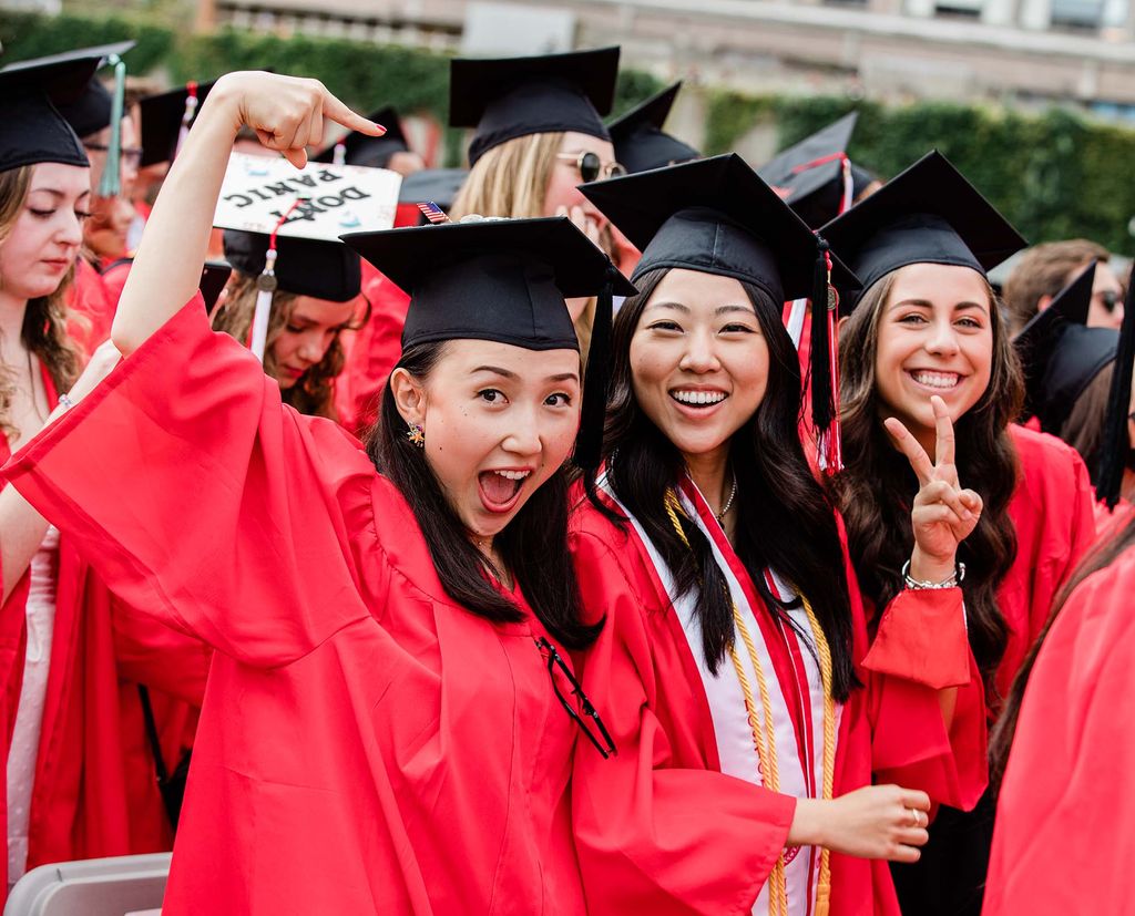 Smiling Boston University students wearing graduation gowns and caps pose for a photo during BU's 147th Commencement.