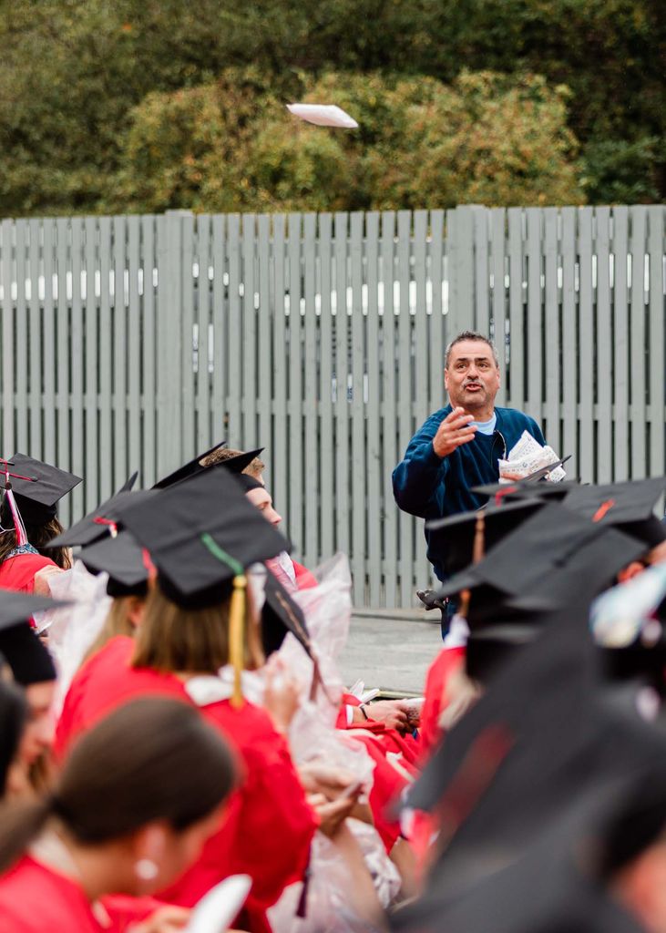 A man throws rain ponchos to graduating students during Boston University's Class of 2020 Commencement ceremony.