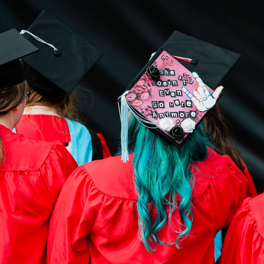 A BU Class of 2020 graduate with blue hair wears a mortarboard cap that says 'She doesn't even go here anymore' during Boston University's 147th Commencement ceremony.