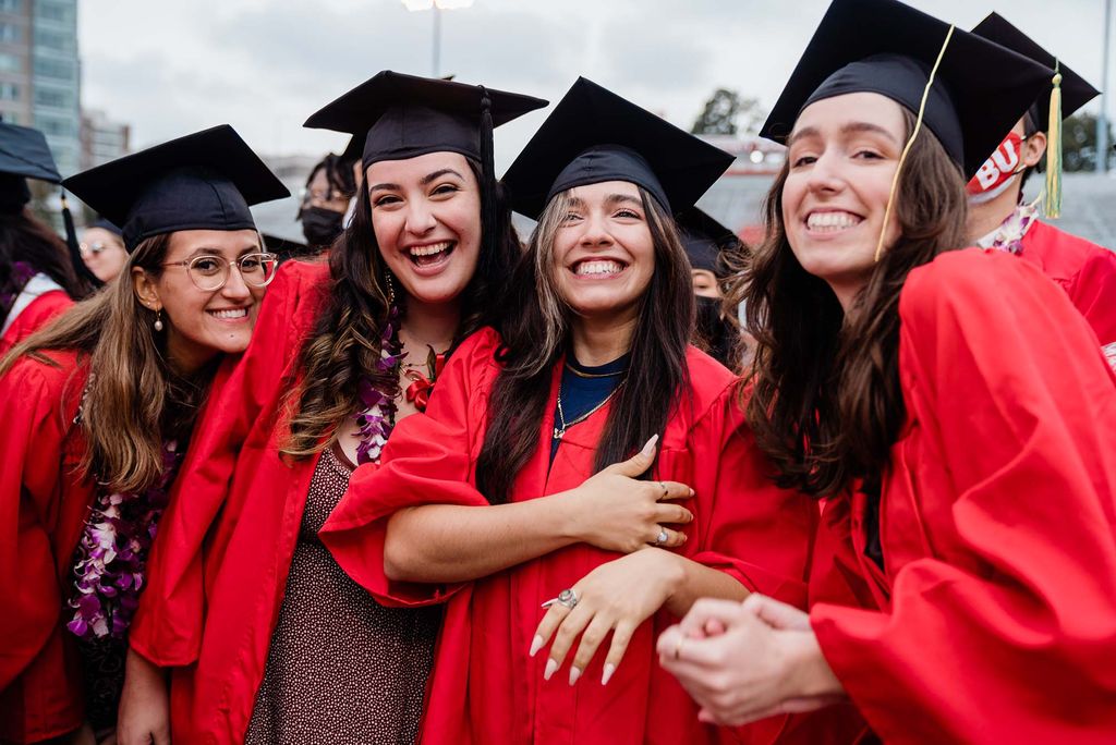 Four BU Class of 2020 graduates pose for a photo in their caps and gowns.