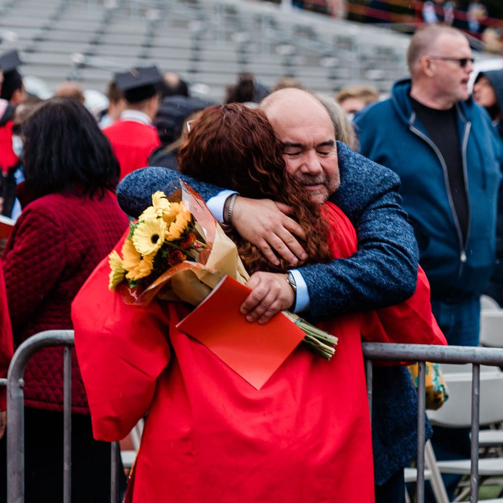 A student hugs a family member following Boston University's 147th Commencement.