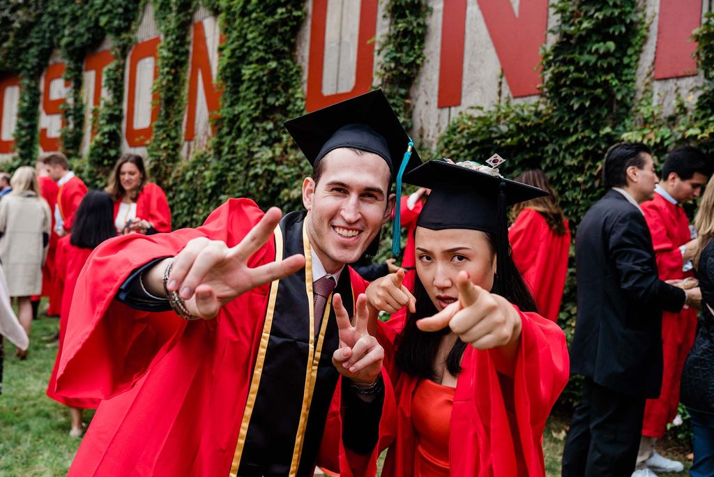 BU Class of 2020 graduates flash peace signs and point at the camera following graduation.
