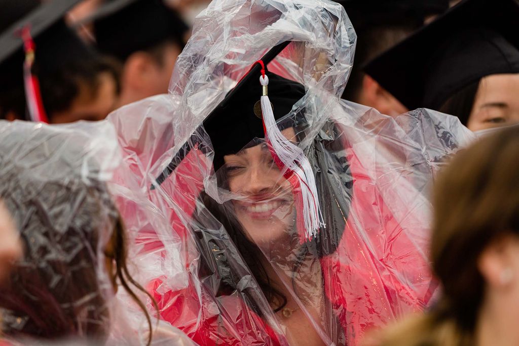 A student pulls a poncho over her head during Boston University's Commencement for the Class of 2020.