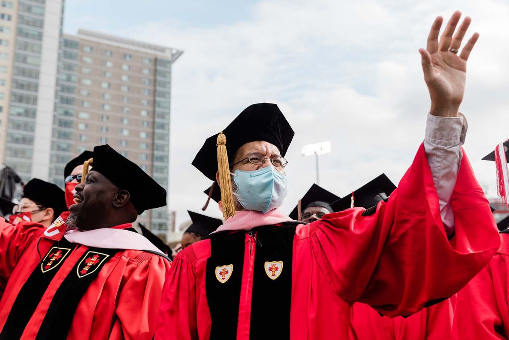 Boston University faculty wearing ceremonious caps and gowns wave during Boston University's 147th Commencement ceremony.