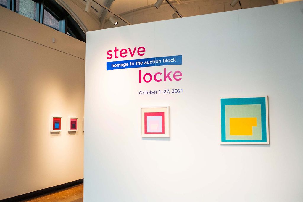 Entrance to the Steve Locke exhbit, Homage to the Auction Block, at Boston University's Stone Gallery. A wall displays the title of the exhibition and two small, colorful works of art.