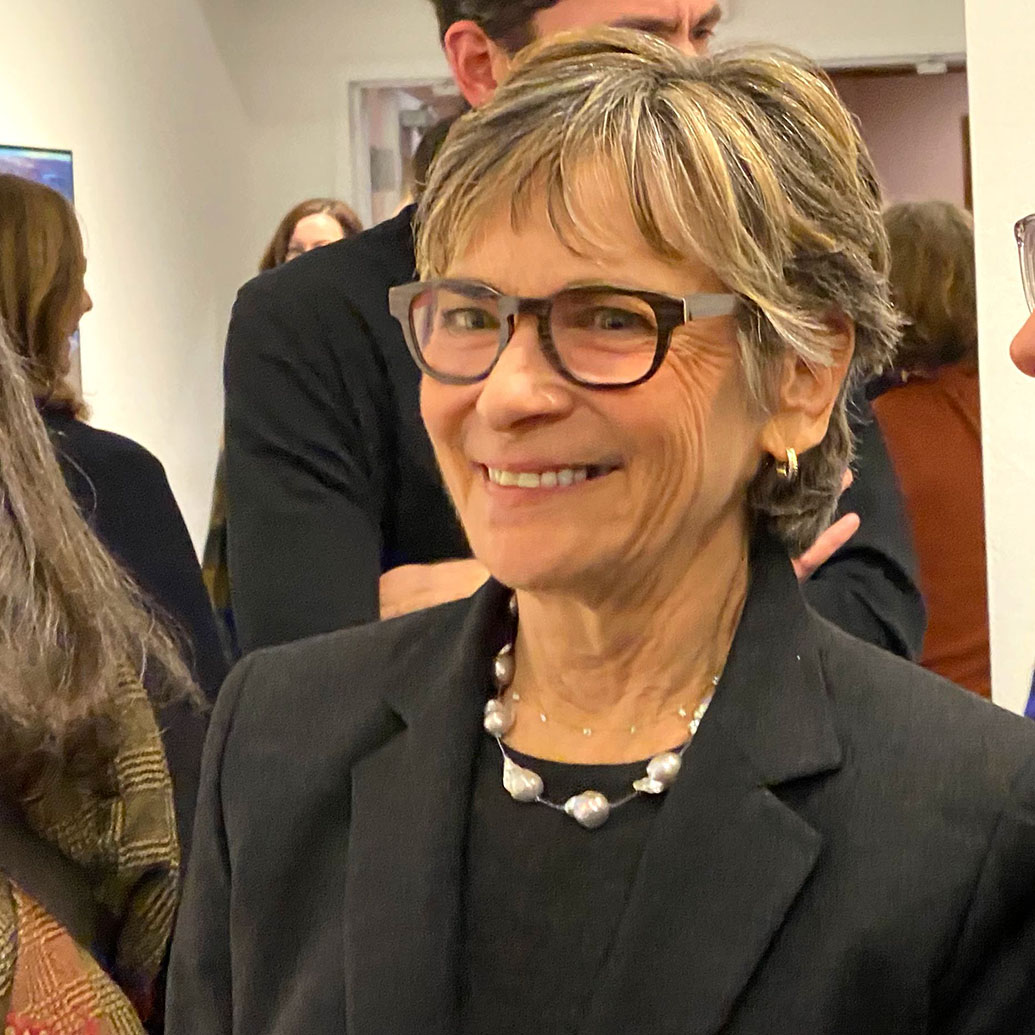 Candid photo of artist Peri Schwartz. She looks to left and smiles to someone off camera