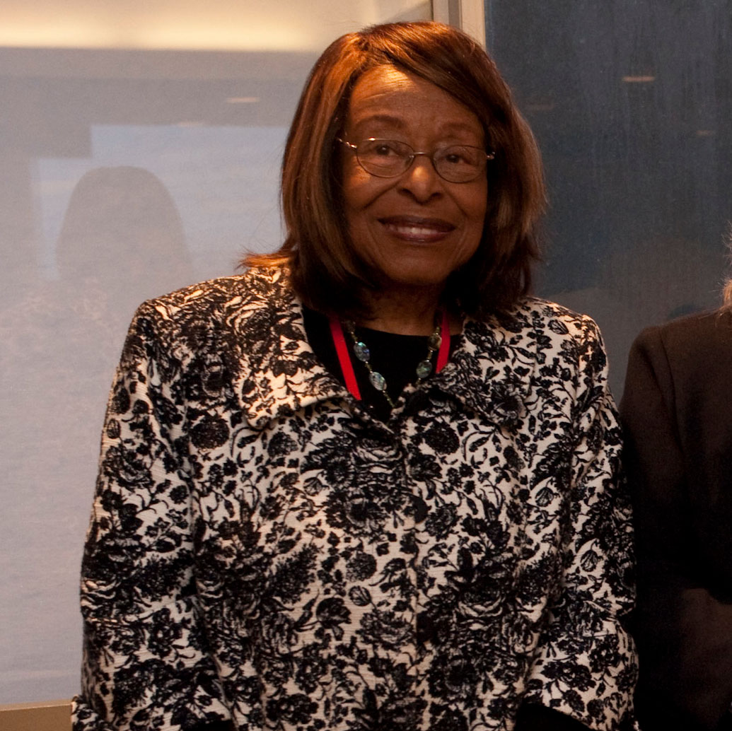 Photo trailblazer Esther Hopkins. She wears a black and white floral blazer and smiles at the camera