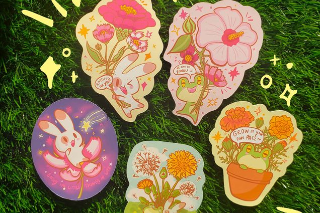Overhead photo a various stickers on lush green grass. Stickers feature cute cartoons of rabbits