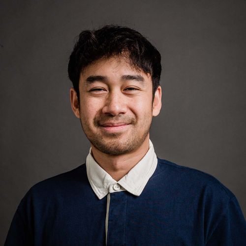 Photo of Koeun Neak, a young asian american man with short black hair. He smiles and wears a blue shirt with a white collar.