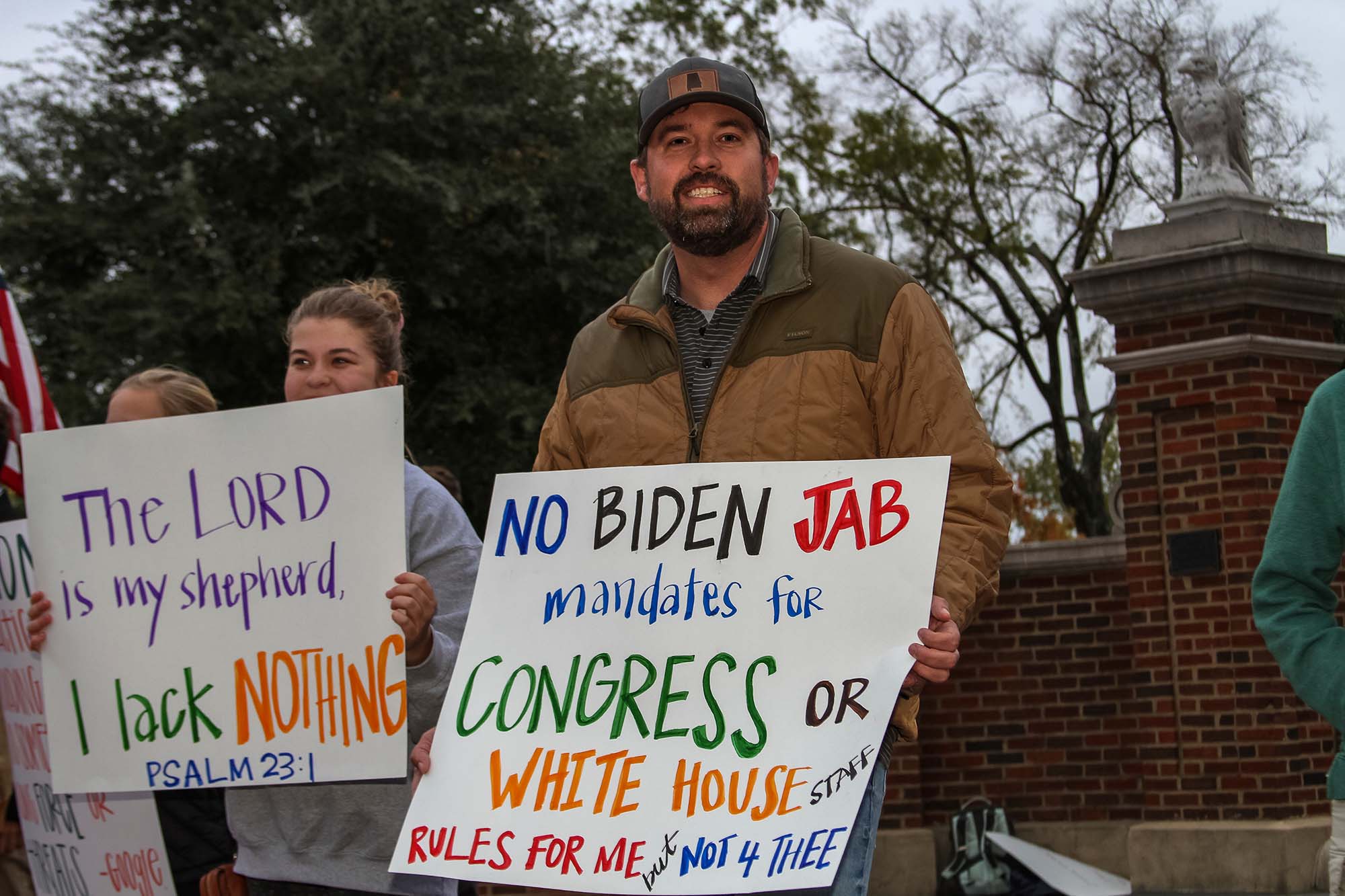 Photo of people protesting vaccine mandates in Auburn, Ala., last fall. A man wearing a tan jacket and hat holds a sign that reads "No Biden Jab mandates for Congress or White House staff. Rules 4 Me but not for Thee"