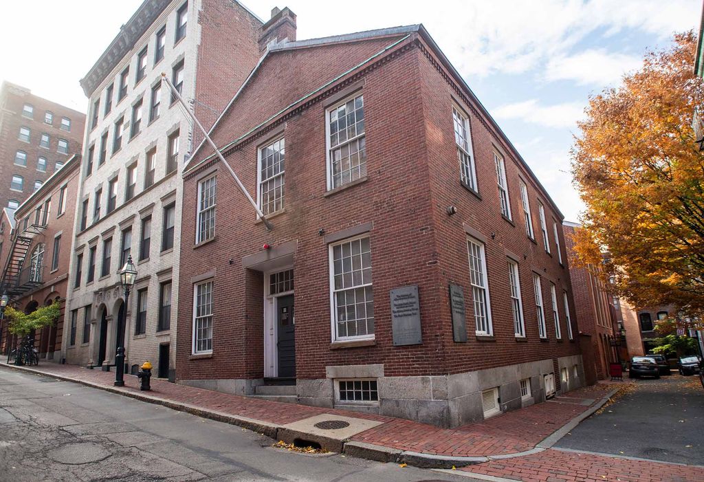 Photo of the exterior of the The Museum of African American History (MAAH) on Joy Street in Boston, an old brick building on a corner with a brick-laden sidewalk.